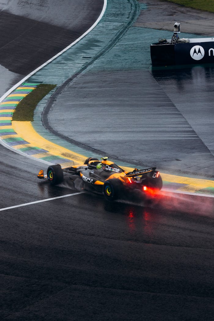A race car speeds through a wet track, showcasing dynamic motion and excitement.